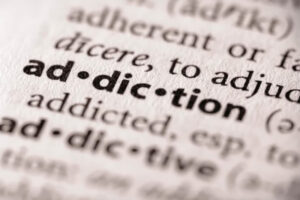 Dictionary opened to the definition of addiction