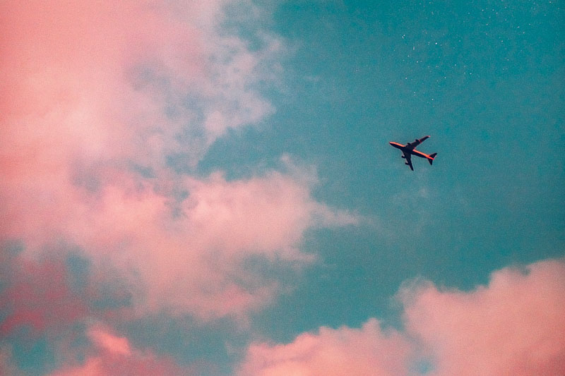 Airplane flying through pink clouds