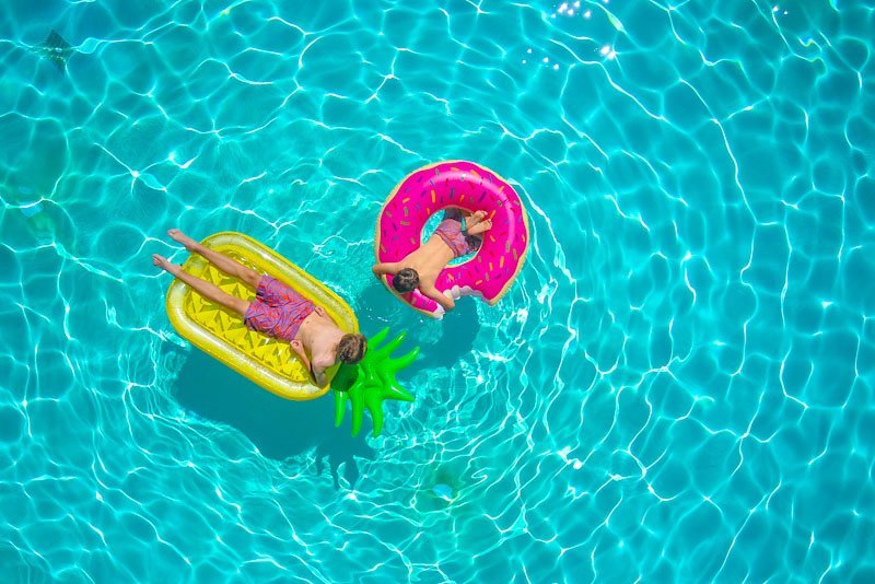 Two men floating on rafts in a pool
