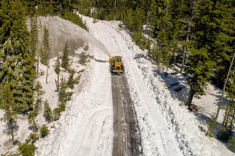 Snowplow clearing a path on a road in the forest