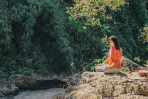 Woman meditating by a waterfall