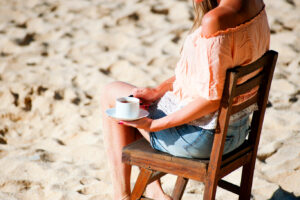 Sober curious woman sitting on the beach with coffee