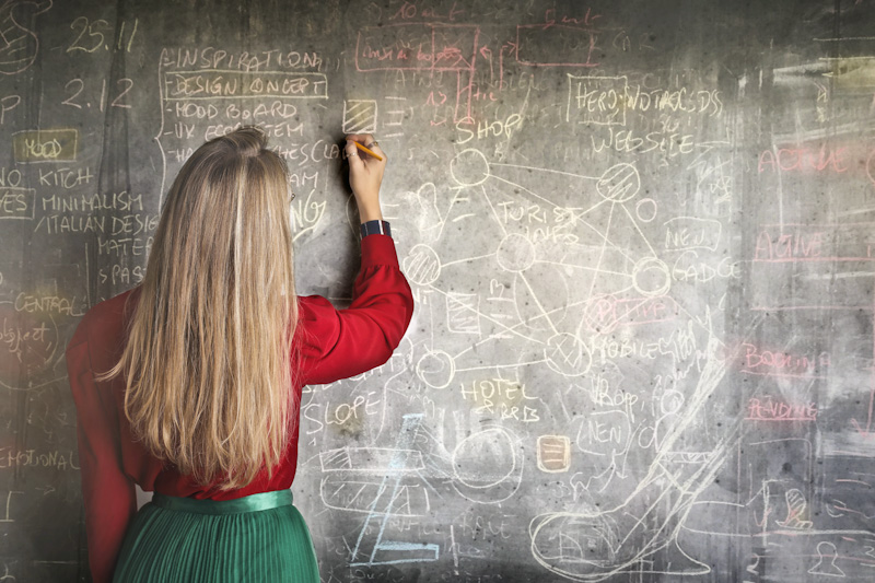 Woman writing on chalkboard at school