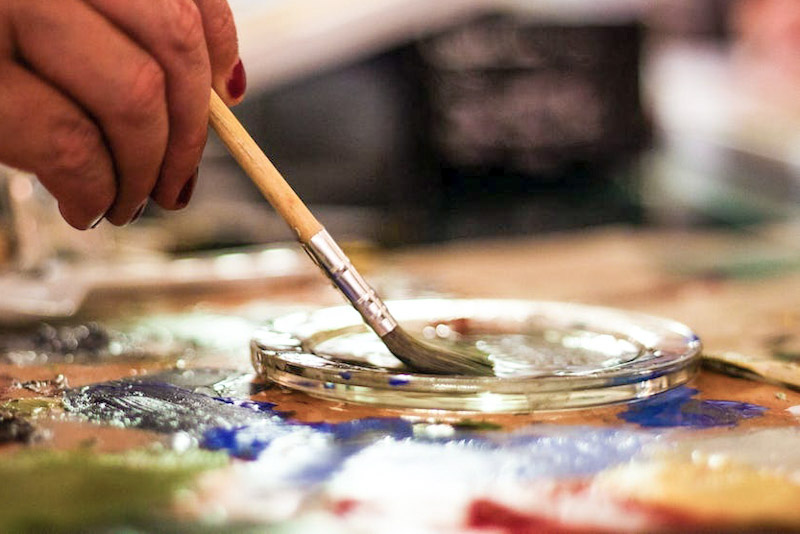 Hand dipping paintbrush into palette