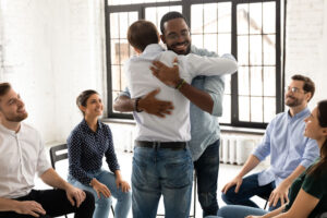 Men hugging at a 12-step recovery meeting